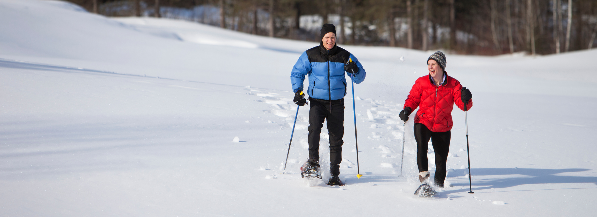 two people snowshoeing across an open field