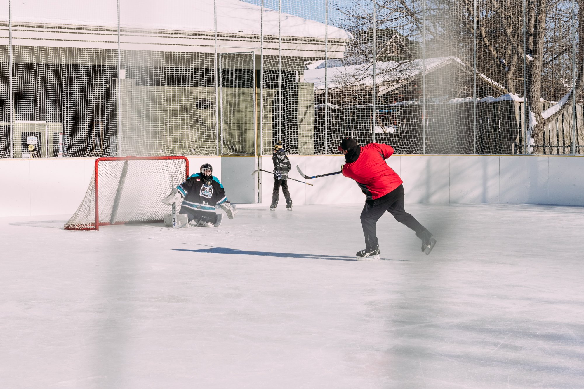 three people playing hockey at the Washago Community Centre outdoor rink 