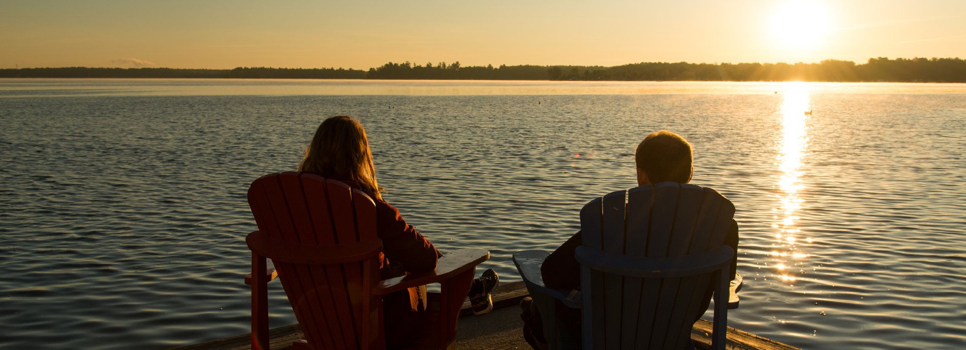 couple in chairs on a dock at sunset