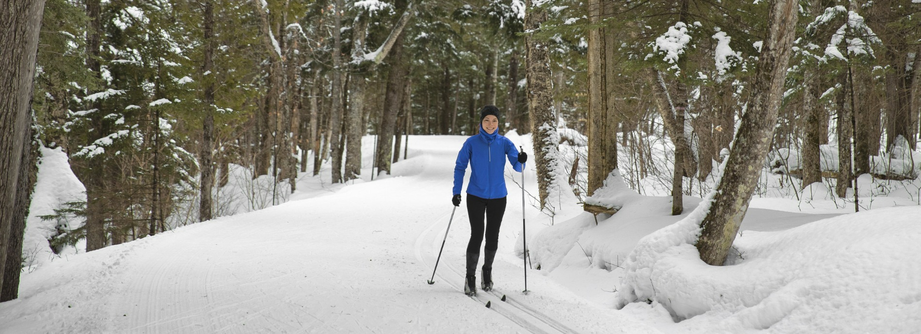 woman cross country skiing through a well treed trail in winter